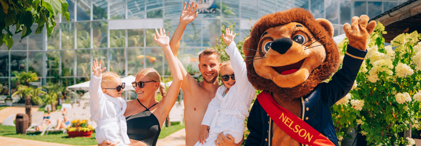 Parents with two children are standing in the spa garden with Nelson, cheering.
