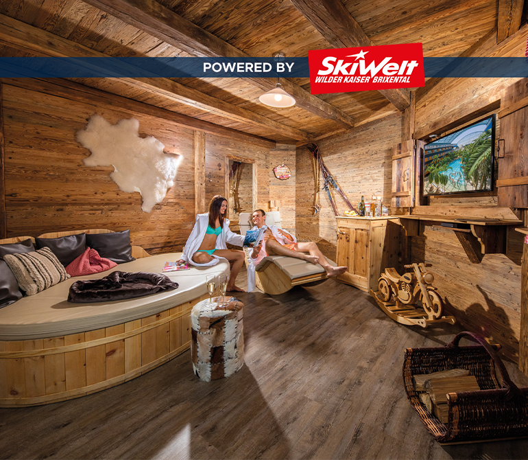 Ein großer Raum in Holzhütten-Optik mit einem großen runden Bett, einer Liege und einem Holz-Schaukelmotorrad.