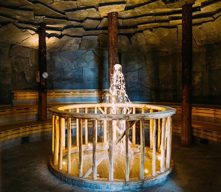 Inmitten der runden Geysirhöhle mit steinernen Wänden ist ein sprudelnder Wasserbrunnen 