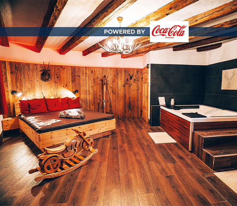 Ein großes Holzbett in einem Raum im Hüttenstil mit Whirlpool und Holz-Schaukelmotorrad.