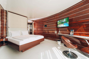 Moderne Yacht-Kabine im Hotel Victory der Therme Erding mit elegantem Holzwanddesign, großem Bett, Flachbildfernseher und Schreibtisch