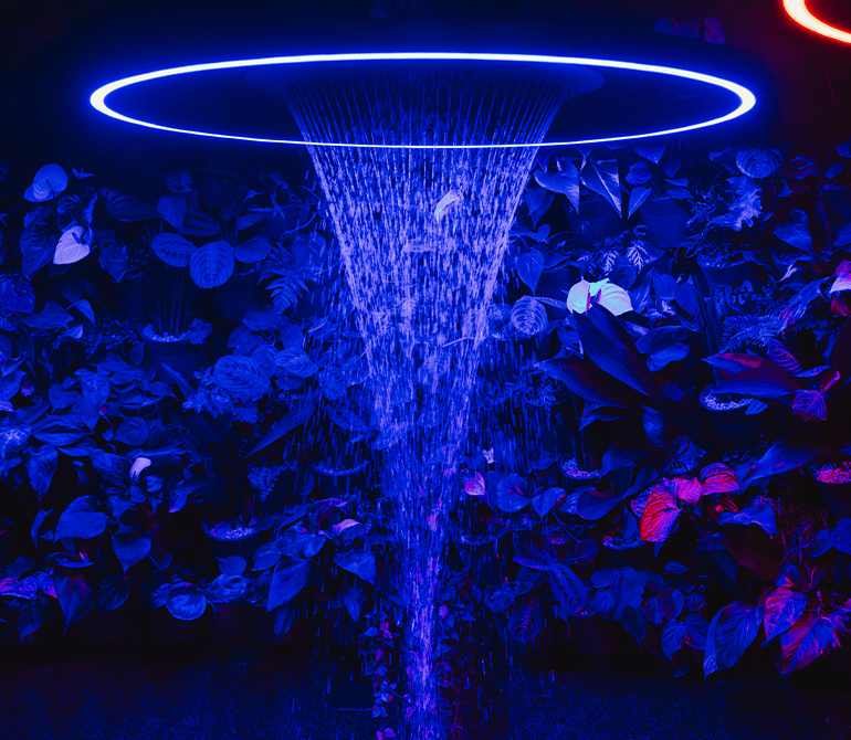 A shower jet glowing blue, with living walls in the background.