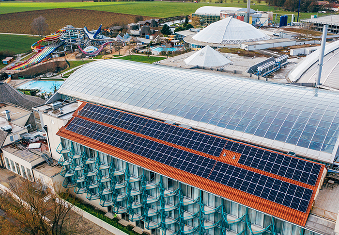Hotel mit Solarpaneelen auf dem Dach neben der Therme Erding mit Wasserrutschen und Kuppelgebäuden