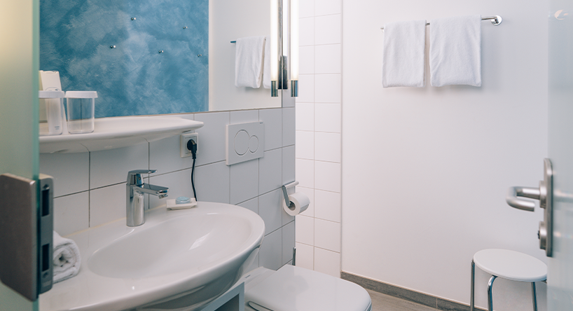 Badezimmer Victory Gästehaus Therme Erding Modernes Badezimmer mit Waschbecken, Spiegel, Handtüchern und WC. Badezimmer-Design im VICTORY GÄSTEHAUS Appartement.