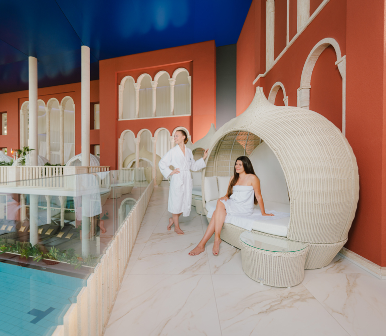 Two women are relaxing in a large white relaxation pod