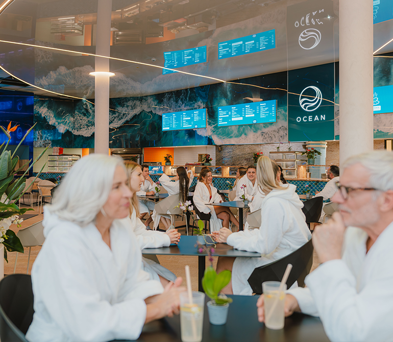 Several guests are sitting in bathrobes at the Ocean Restaurant in the spa.