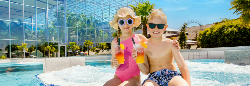 Zwei Kinder sind im Crazy River und trinken einen Kindercocktail.