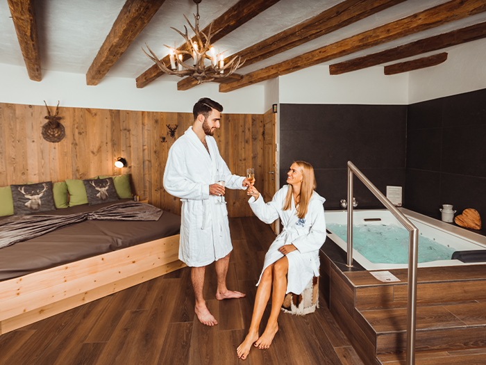 Couple in a cozy lounge in an alpine hut style with a whirlpool.