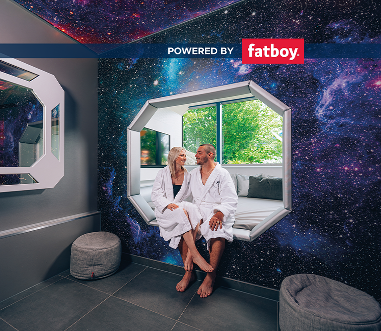 Ein Paar entspannt gemeinsam auf einer Liege in einem Raum mit futuristischem Weltraumdesign.