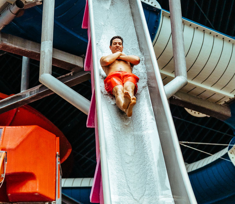 Man slides down the almost vertical Kamikaze slide.