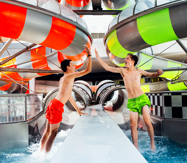Two children stand in the landing pool of the Speed Racer and clap their hands happily.