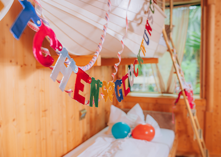 Dekogirlande mit der Aufschrift "Herzlichen Glückwunsch" und bunte Luftballons sind in Hotelzimmer verteilt