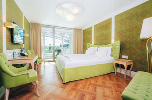 Zimmer Serenissima im Hotel Victory Therme Erding: stilvolles Doppelbett, Fernseher, Tisch und Balkon