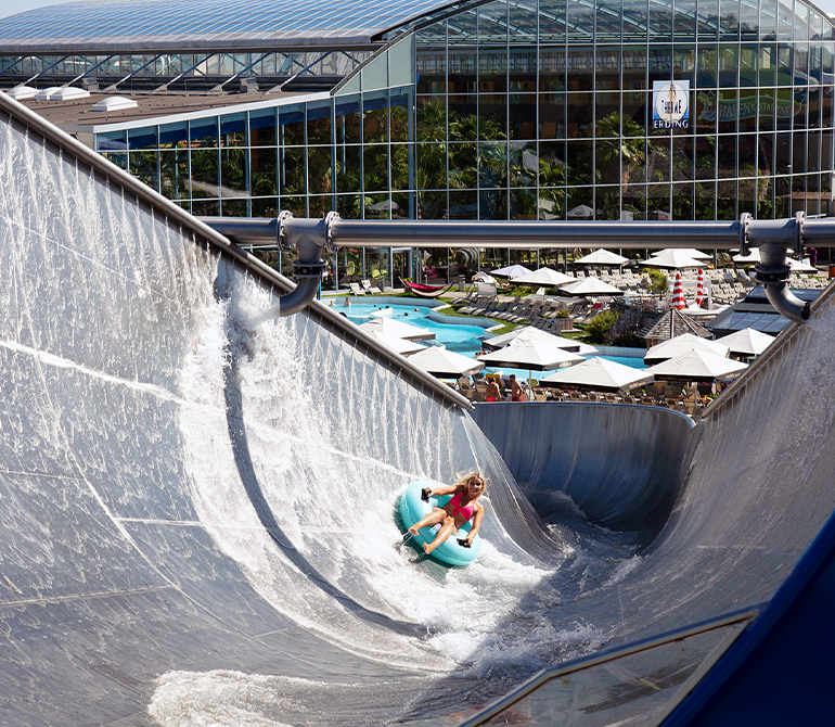 A woman slides down the largest half-pipe slide in the Thermengarten on a inner tube.