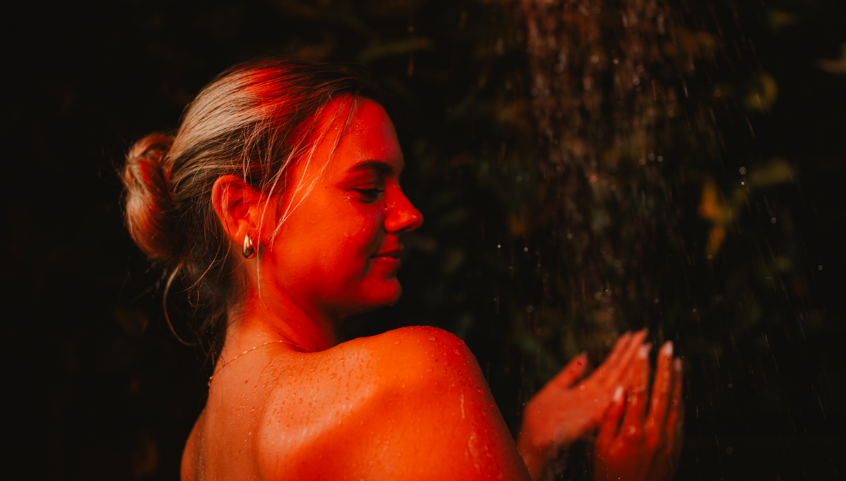 Eine Frau steht entspannt unter der Dusche und genießt das warme Wasser.