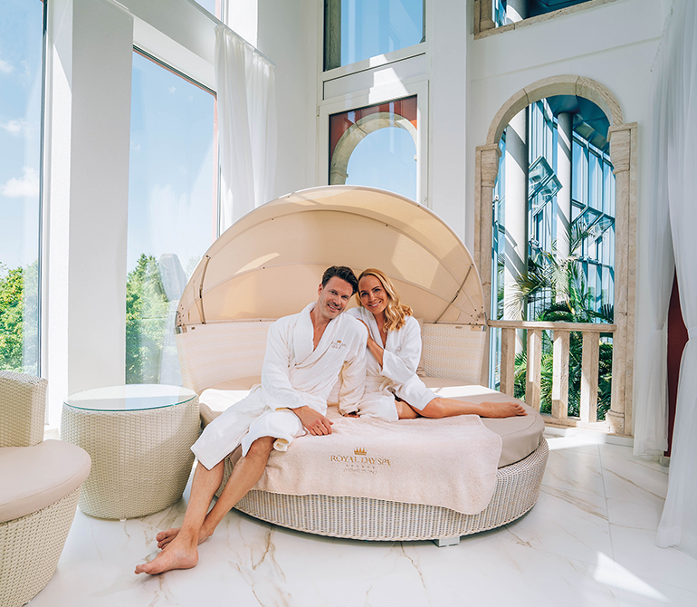 A couple in bathrobes sits in a private suite, enjoying some quality time together. 