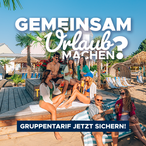 Eine Gruppe Freunde sitzt im Thermengarten gemeinsam auf einer Holzbank.
